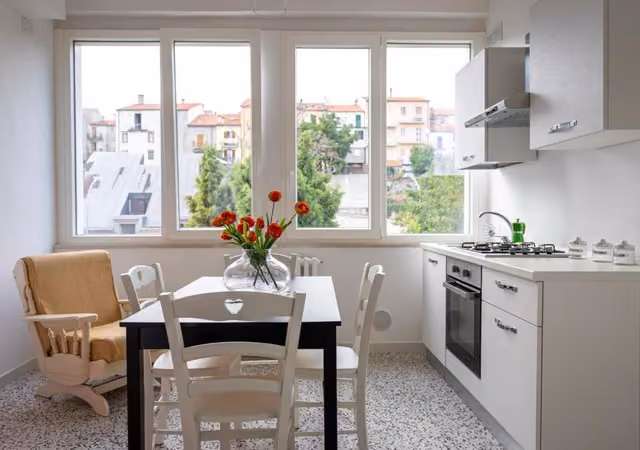 Cucina con tavolo e vaso di fiori del B & B L'ABBRACCIO